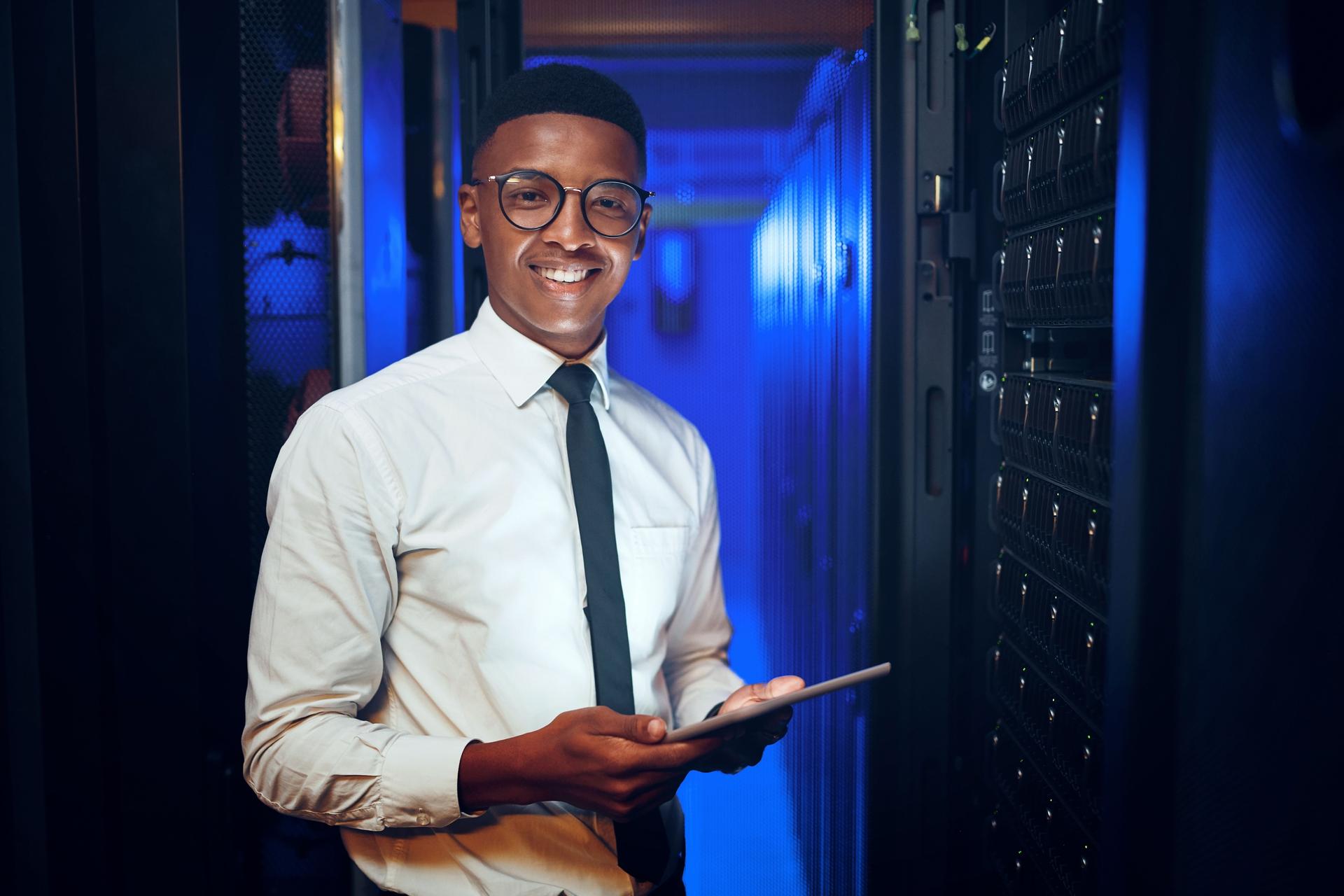 Portrait of a young man using a digital tablet while working in a server room